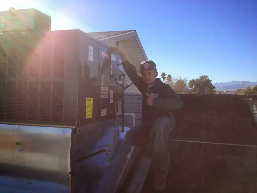 HVAC technician performing Air Duct Cleaning on a rooftop unit in Spring